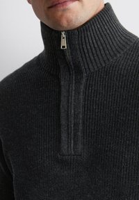 Charcoal gray zip-neck pullover in ribbed texture. Features a high collar and a metal zipper for closure, providing a snug fit.