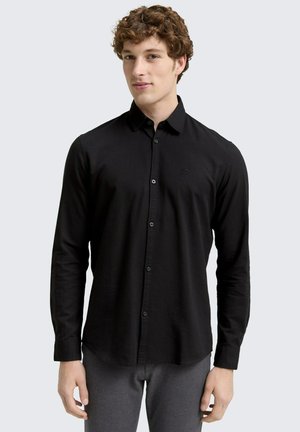 Camicia nera a maniche lunghe con bottoni, realizzata in tessuto strutturato, con bottoni neri a contrasto e un piccolo logo sul petto.