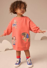 Robe sweat en corail avec des motifs animaliers brodés : un lapin, une souris et un chien. Accompagnée de baskets montantes bleues et blanches.