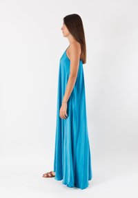 Abito maxi senza maniche di un luminoso blu, realizzato in tessuto morbido e fluente. Presenta una vestibilità ampia che cade elegantemente fino al pavimento.