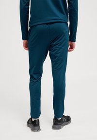 Teal sportbroeken gemaakt van gladde stof, met een taps toelopend ontwerp, een elastische tailleband en reflecterende accenten aan de zijkant.