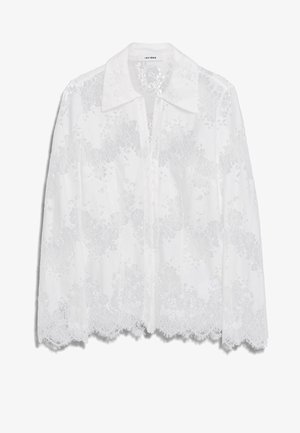 Blouse en dentelle blanche avec un col, fermeture à boutons et motifs floraux délicats avec des bords festonnés. Tissu léger et translucide.