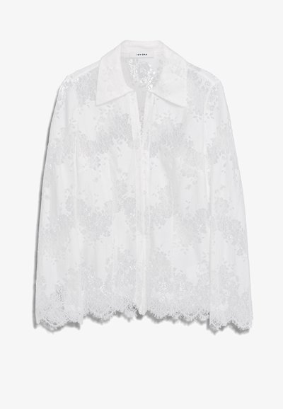White lace blouse featuring a collared neckline, button front, and intricate floral patterns with scalloped edges. Lightweight, translucent fabric.