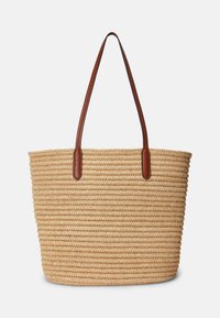 Tkaná slámová taška s hnědými koženými držadly. Kulatý tvar, texturovaný povrch a přírodní barva. Žádné viditelné zapínání ani ozdoby.