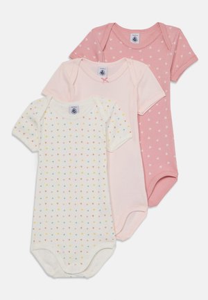 Tre kortärmade bodysuits i rosa nyanser; en enfärgad rosa med hjärtan, en ljusrosa, en krämfärgad med mönster av flerfärgade hjärtan. Cottonsmaterial.