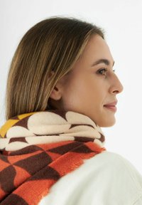 Multicolored sjaal met een patroon in bruin, crème, oranje en gele tinten. Gemaakt van zacht materiaal met franjes en een geometrisch ontwerp.