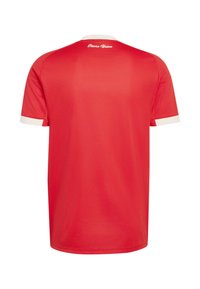 Maillot de sport rouge avec col et poignets de manches blancs, vu de dos, affichant le texte "Eisern Union" près de l'encolure.