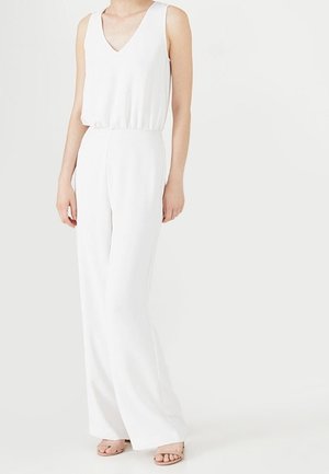 Witte mouwloze jumpsuit met een diepe V-hals en een elastische taille. Wijde pijpen, gladde stoftextuur en subtiele plooidetails.