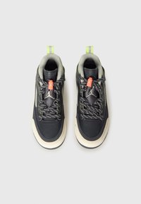 Črni usnjeni športni čevlji s sivimi poudarki, elastičnimi vezalkami, svetlo oranžnim zatikom in zelenim zankom na peti. Debel gumijast podplat.