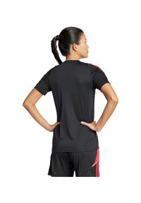 Maglia atletica nera a maniche corte, con dettagli rossi sulle spalle e sui lati, realizzata in un materiale leggero e traspirante.