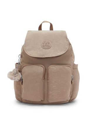 Zaino beige con patta superiore, due tasche frontali con zip, tasche laterali e un piccolo portachiavi peluche a forma di scimmia attaccato sul lato sinistro.