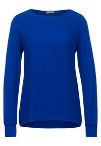 Långärmad blå topp gjord av slät tyg, med rund hals och något böjd nederkant. Har åtsittande ärmar med elastiska manschetter.