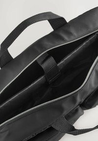 Borsa nera con zip realizzata in tessuto resistente, dotata di un ampio interno con due scomparti e manici in tessuto rinforzato per un facile trasporto.
