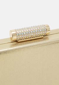 Gold metallic clutch with a textured surface, featuring a sparkling rhinestone-encrusted clasp. Rectangular shape and sleek design.