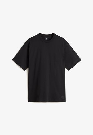 Black short-sleeve T-shirt made of cotton. Features a round neckline and a small logo patch at the lower left hem. Smooth texture.