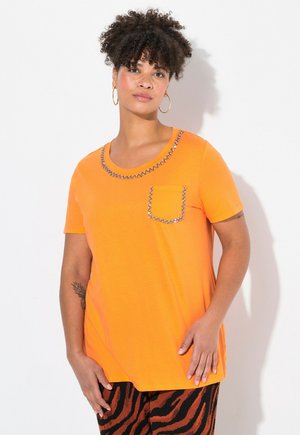 Orange kortærmet T-shirt med rund halsudskæring, pyntet kant og en dekorativ lomme. Blødt stof og løs pasform.