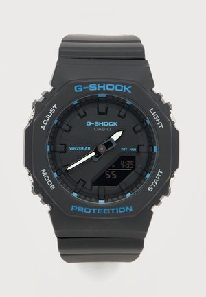 Μαύρο ρολόι Casio G-Shock με μπλε λεπτομέρειες, αναλογικά δείκτες που δείχνουν 4:38, ψηφιακή οθόνη και κουμπιά με ετικέτες για ρύθμιση, λειτουργία, φως και εκκίνηση.