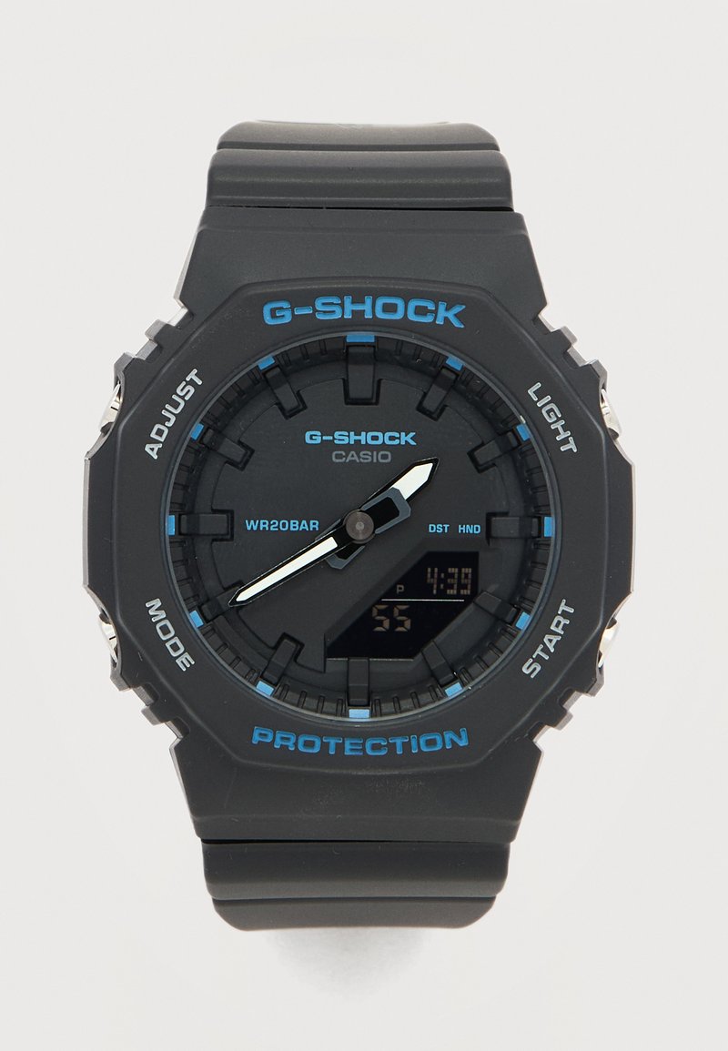 Μαύρο ρολόι Casio G-Shock με μπλε λεπτομέρειες, αναλογικά δείκτες που δείχνουν 4:38, ψηφιακή οθόνη και κουμπιά με ετικέτες για ρύθμιση, λειτουργία, φως και εκκίνηση.