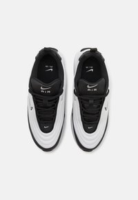 Zwart-witte Nike sneakers met een textuur bovenkant, vetersluiting en opvallende zool. "AIR" branding op de tong en inlegzool.