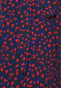 Tessuto nero con un audace design animalier leopardato rosso e blu, caratterizzato da una superficie liscia e un'ottima caduta. Le aperture forniscono continuità al motivo.