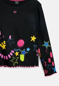 Schwarzes Langarmoberteil mit geripptem Material, das farbenfrohe Sterne und abstrakte Muster in Pink, Gelb und Blau zeigt, mit volantsaum.
