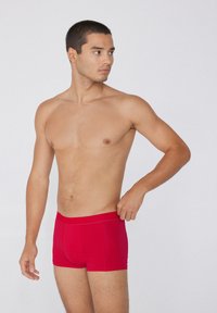 Červené plavecké šortky s přiléhavým střihem. Vyrobené z hladkého materiálu s měkkým pasem. Minimální akcenty švů. Rovné nohavice.