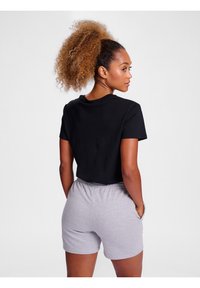 Tricou negru scurt cu mâneci scurte, asociat cu pantaloni scurți gri cu talie elastică. Material neted, cu o croială lejeră, potrivit pentru uz casual.