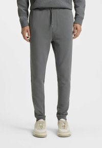 Gray sweatpants made from soft fabric, featuring an elastic waistband with a drawstring, cuffed legs, and side pockets.
