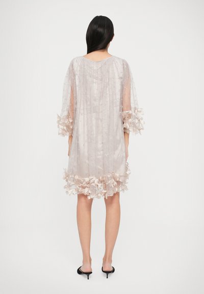 Robe beige légère avec des accents floraux aux manches et à l'ourlet, agrémentée de petites paillettes, présentant une coupe ample et une longueur mi-mollet.