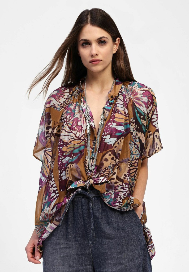 Blusa a fantasia di farfalle marrone e viola con vestibilità ampia, dotata di un laccio in vita e maniche corte, realizzata in tessuto leggero.