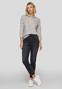 Striped long-sleeve polo in gray and white, with a collar and a pocket; paired with dark jeans and white sneakers. Simple, fitted design.