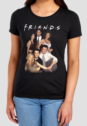 Schwarzes T-Shirt mit Gruppenfoto und Logo der Besetzung der TV-Serie Friends, getragen von einer Person in blauen Jeans.