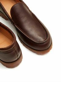 Scarpe slip-on in pelle marrone con tomaia liscia, punta tonda e suola in gomma con battistrada testurizzato. Nessun marchio visibile.