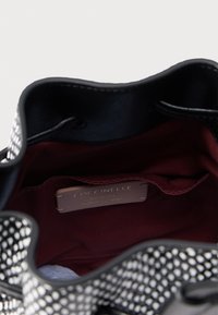 Μαύρη δερμάτινη τσάντα με λευκό πουά σχέδιο. Το εσωτερικό διαθέτει μπορντό υφασμάτινη επένδυση και δερμάτινη ετικέτα που υποδεικνύει αυθεντικό ιταλικό δέρμα.