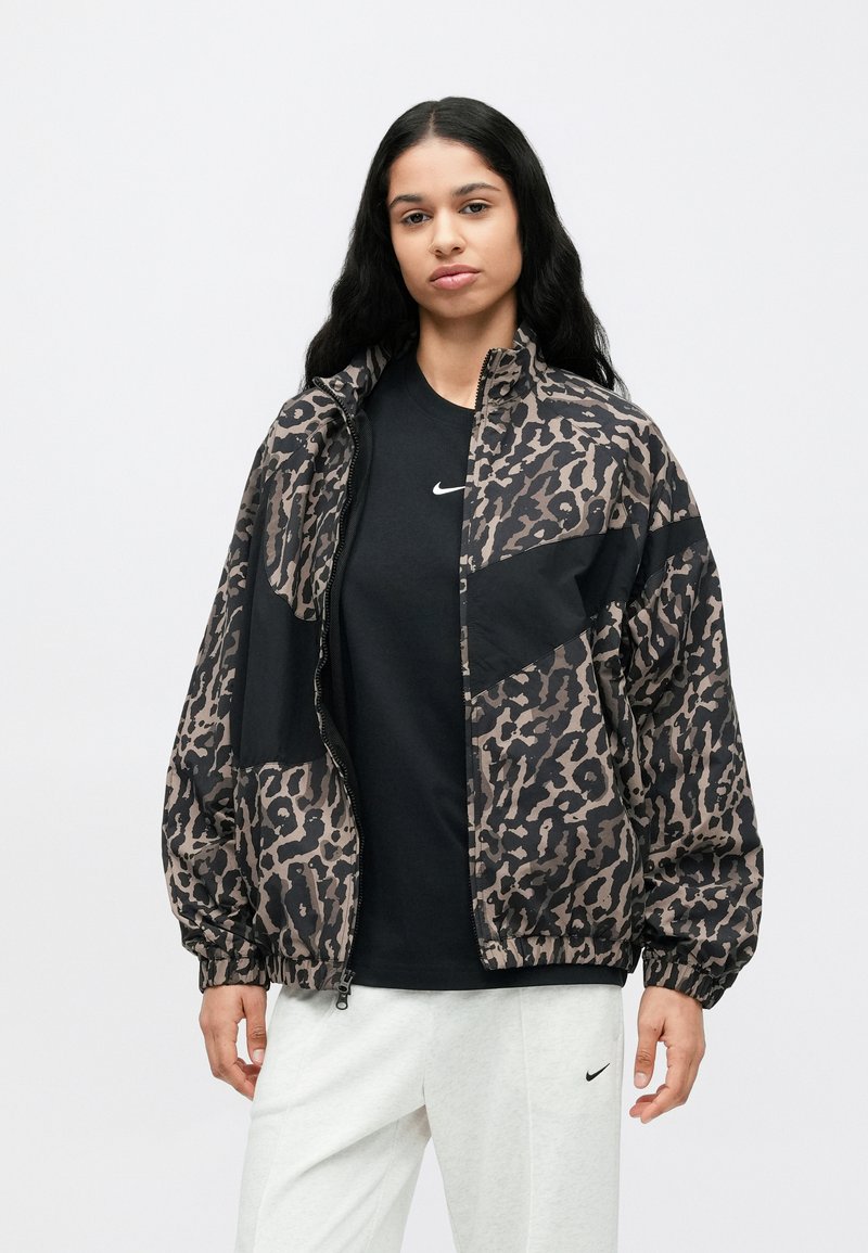 Leopardprint windbreaker jas met een zwart paneel, elastische manchetten en een rits aan de voorkant. Draagt over een zwart T-shirt met een logo.