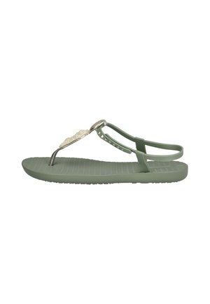 Sandalia plana verde con suela texturizada, tira trasera ajustable y detalle decorativo de perlas en la tira entre los dedos.