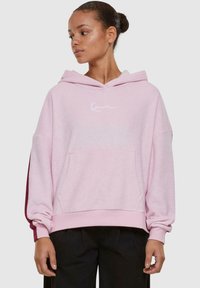 Lichtroze hoodie met een relaxed fit, voorzien van een voorzak en witte logo borduursel. Zacht textuur en lange mouwen.
