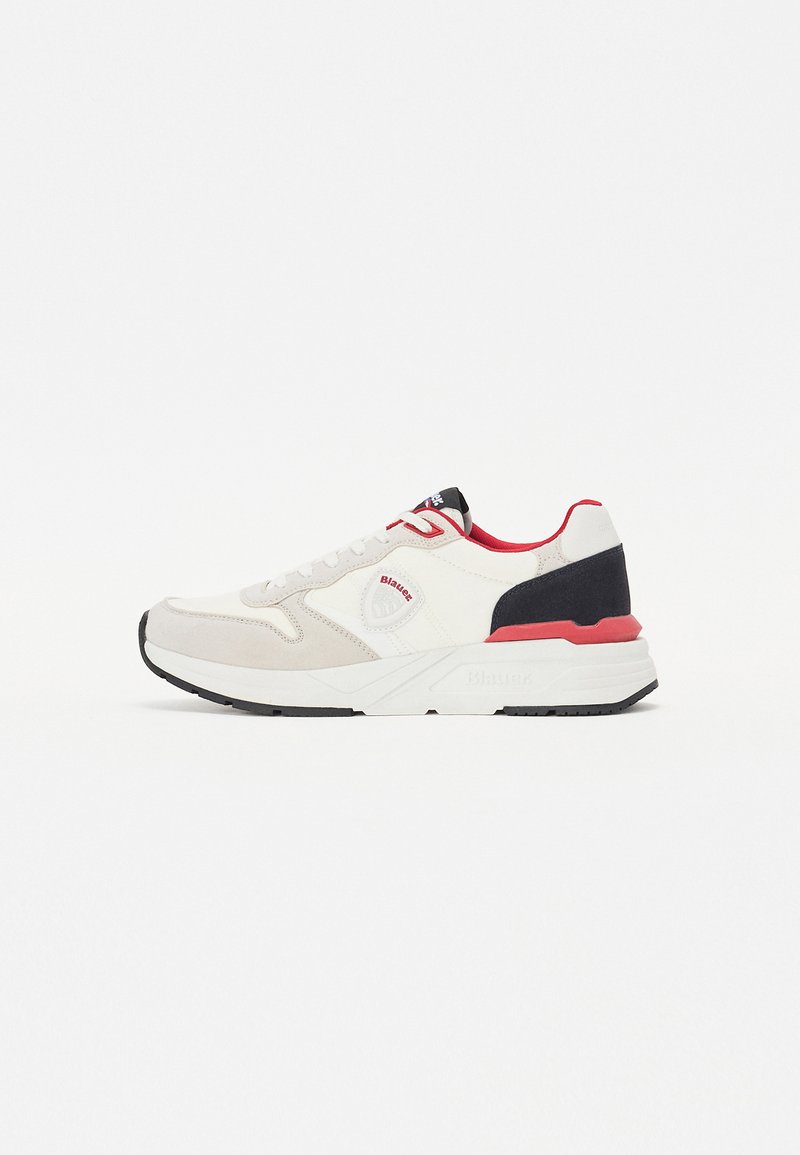 Sneakers bianchi e grigi con accenti rossi e blu navy, dotati di una parte superiore in morbida pelle scamosciata e mesh, con chiusura a lacci e una robusta suola in gomma.