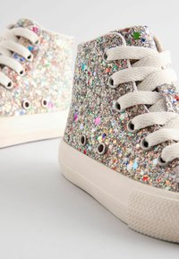Baskets montantes recouvertes de paillettes avec des éclats multicolores, lacets en coton blanc et semelles en caoutchouc. orteil arrondi et œillets visibles.