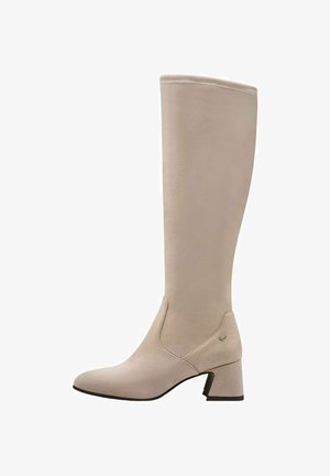 Beige knähög stövel i mjukt mocka, med spetsig tå, klack i blockstil och diskreta sömdetaljer längs sidorna.