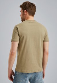T-shirt à manches courtes, col rond, en coton vert olive, avec une coupe décontractée et une texture lisse. La vue arrière montre des coutures soignées et un design subtil.