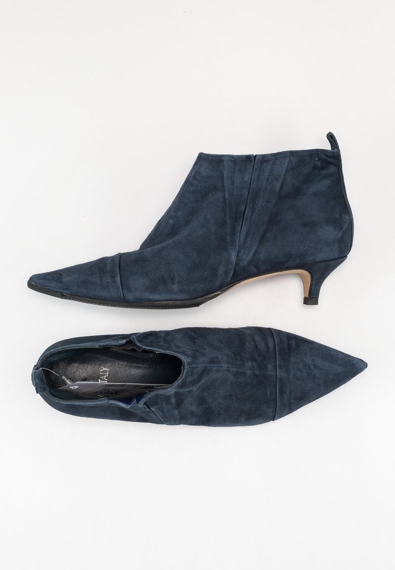 Navy blue suede ankle boots with pointed toes, low heels, and smooth texture. One boot features an elastic side for easy wear.
