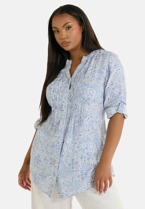Camisa de color azul claro con estampado de paisley, con cuello abotonado, detalles fruncidos y mangas enrolladas, hecha de una tela suave y texturizada.