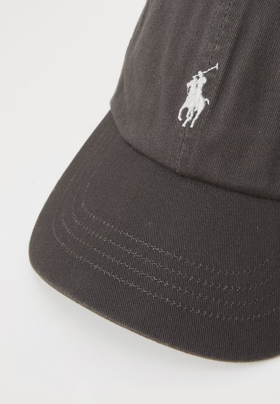 Fekete pamut baseball sapka ívelt karimával, fehér hímzett logóval, amely egy pólójátékost ábrázol. Texturált anyag és látható varrási részletek.