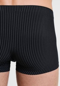 Boxer shorts rayés noirs en tissu doux, dotés d'une ceinture confortable et de rayures verticales pour ajouter de la texture.