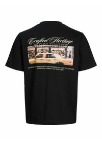 Černé tričko s krátkým rukávem. Na zadní straně je grafika městské scény s žlutým taxíkem a textem "Crafted Heritage Worldwide Originals."