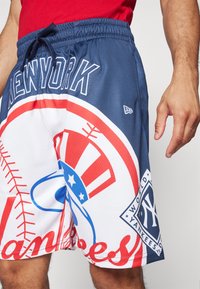 Pantalones cortos de béisbol con un diseño en azul y blanco contrastante, gráficos prominentes de los New York Yankees y una cómoda cintura elástica.