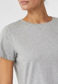 Jasnoszary T-shirt z krótkim rękawem wykonany z miękkiego materiału, z okrągłym dekoltem i gładką teksturą, z minimalnie widocznymi szwami na rękawach.