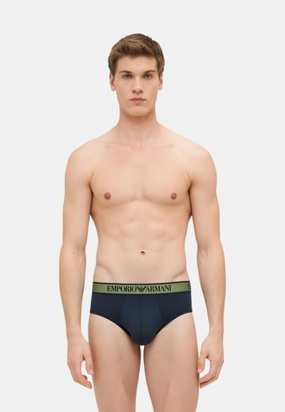 Slip navy blue con un elastico verde che presenta il logo "Emporio Armani", tessuto liscio, design aderente e taglio classico.