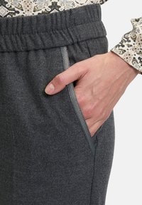 Graue Jogginghose mit elastischem Bund, seitlichen Taschen mit kontrastierendem Besatz und einem weichen, strukturierten Stoff.
